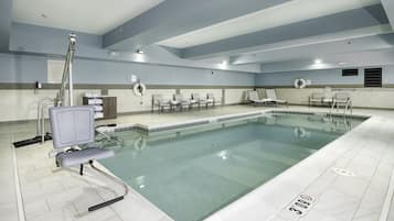 A swimming pool with a lifeguard chair, lounge chairs, and a sign indicating pool rules.