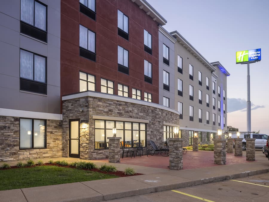 Moderni hotelli, jossa on kiviverhous, useita ikkunoita, ulkotila istumiseen ja selkeästi näkyvä Holiday Inn Express & Suites -kyltti.