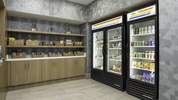 A clean, well-organized snack bar with shelves stocked with various snacks and a refrigerated display case with beverages.