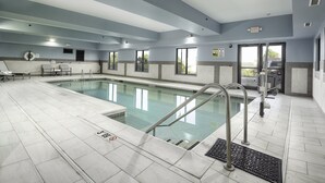 A swimming pool area with a clear pool, a lifeguard chair, and a sign indicating the pool's depth.