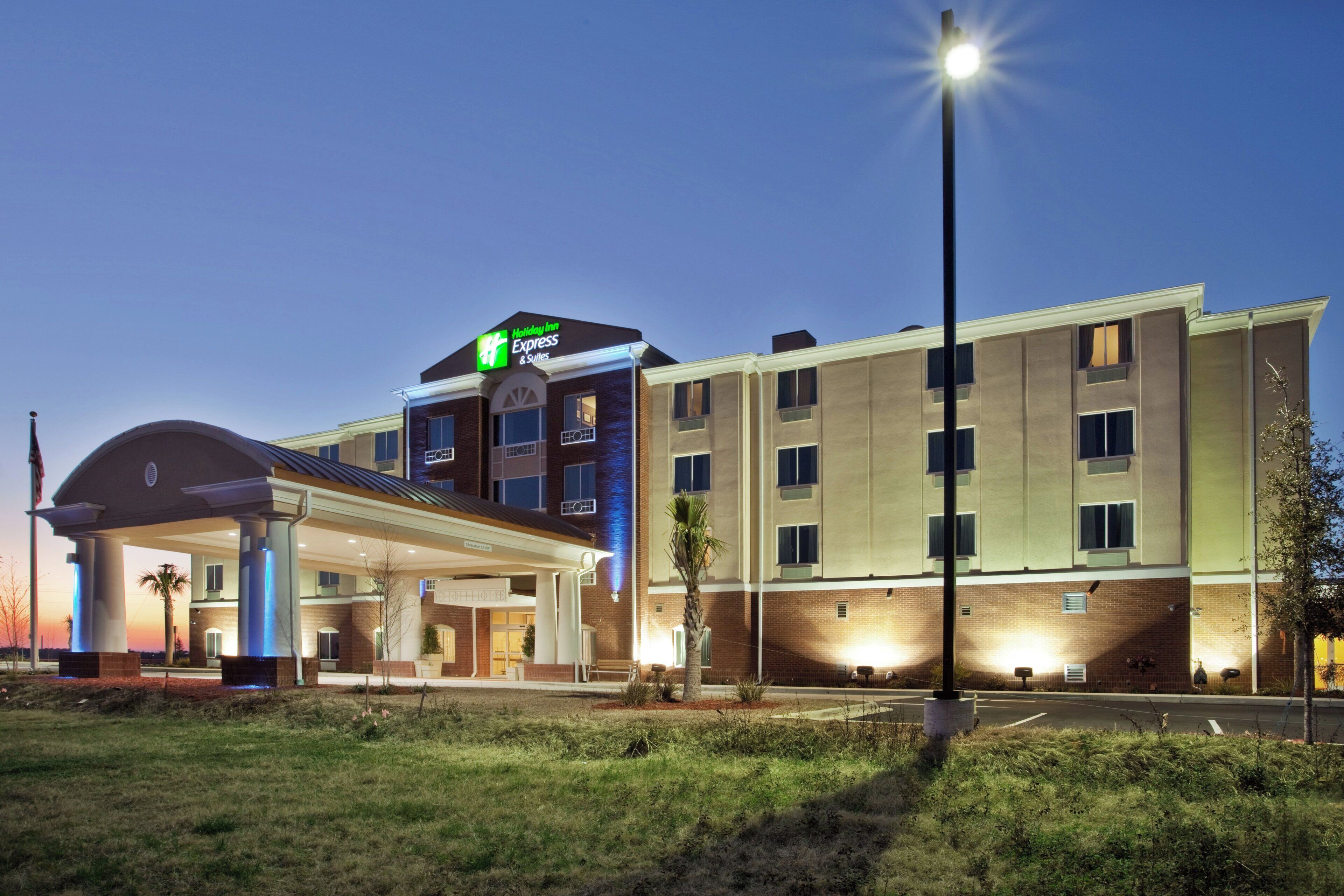 Ein Holiday Inn Express & Suites Hotel mit überdachter Eingangsparte, Parkplatz und Straßenlaterne.