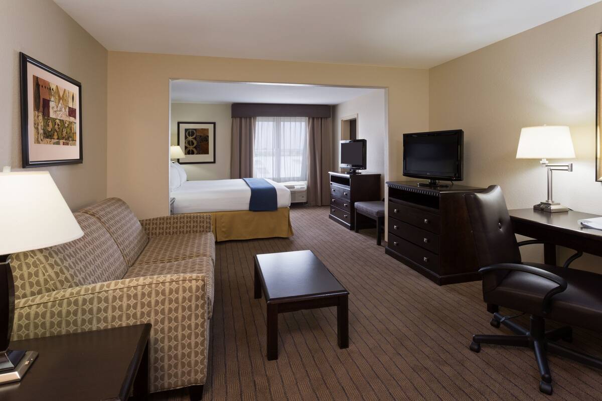 A hotel room with a bed, a sofa, a desk, a television, and a lamp.