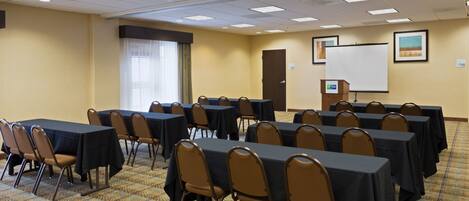 A conference room with tables and chairs, a whiteboard, and a door.