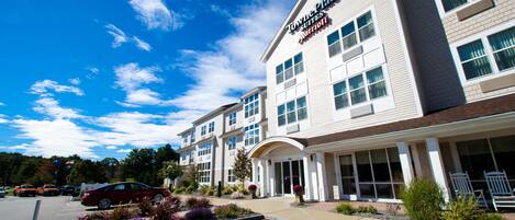 A hotel with a modern design, featuring a large entrance and a parking lot.