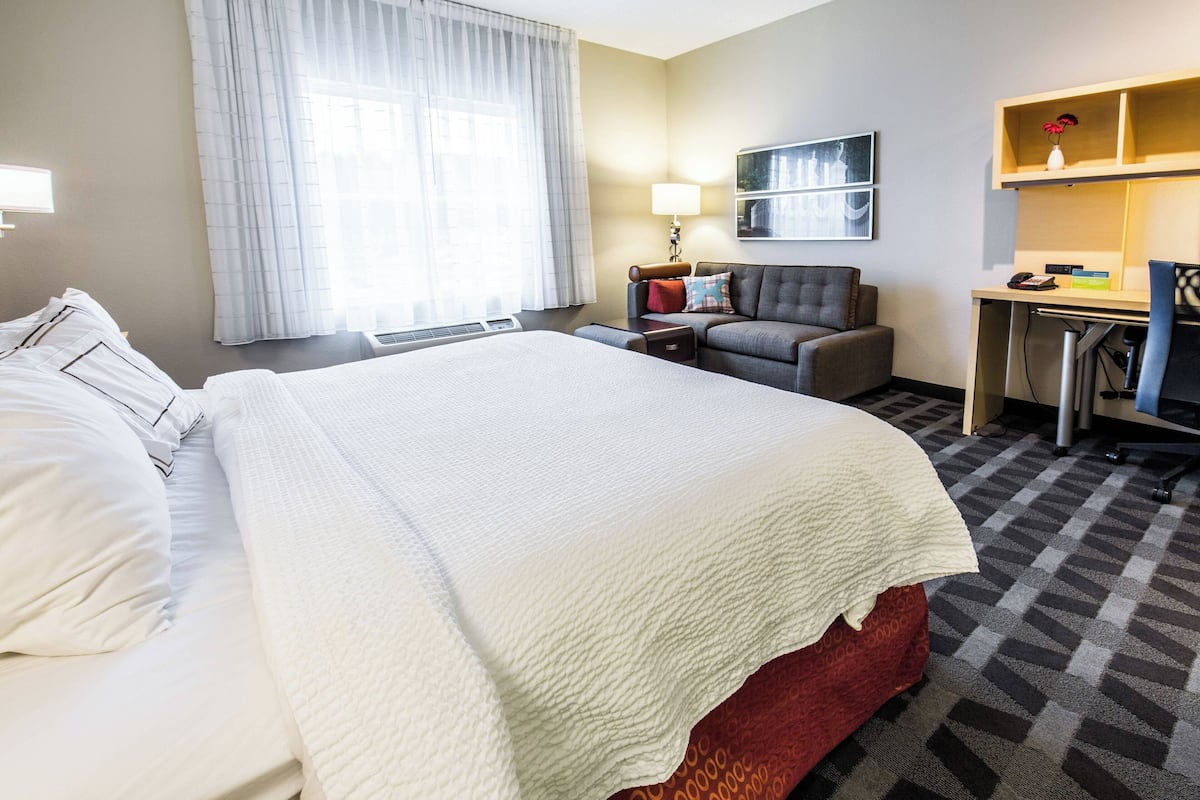Een hotelkamer met een groot bed, een bureau, een stoel en een bank.