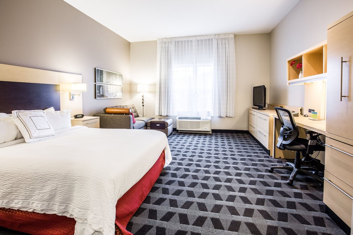 Een hotelkamer met een groot bed, een bureau met stoel, een televisie en een kledingkast.