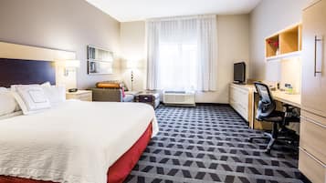Una habitación de hotel con una cama grande, un escritorio con silla, un televisor y un armario.