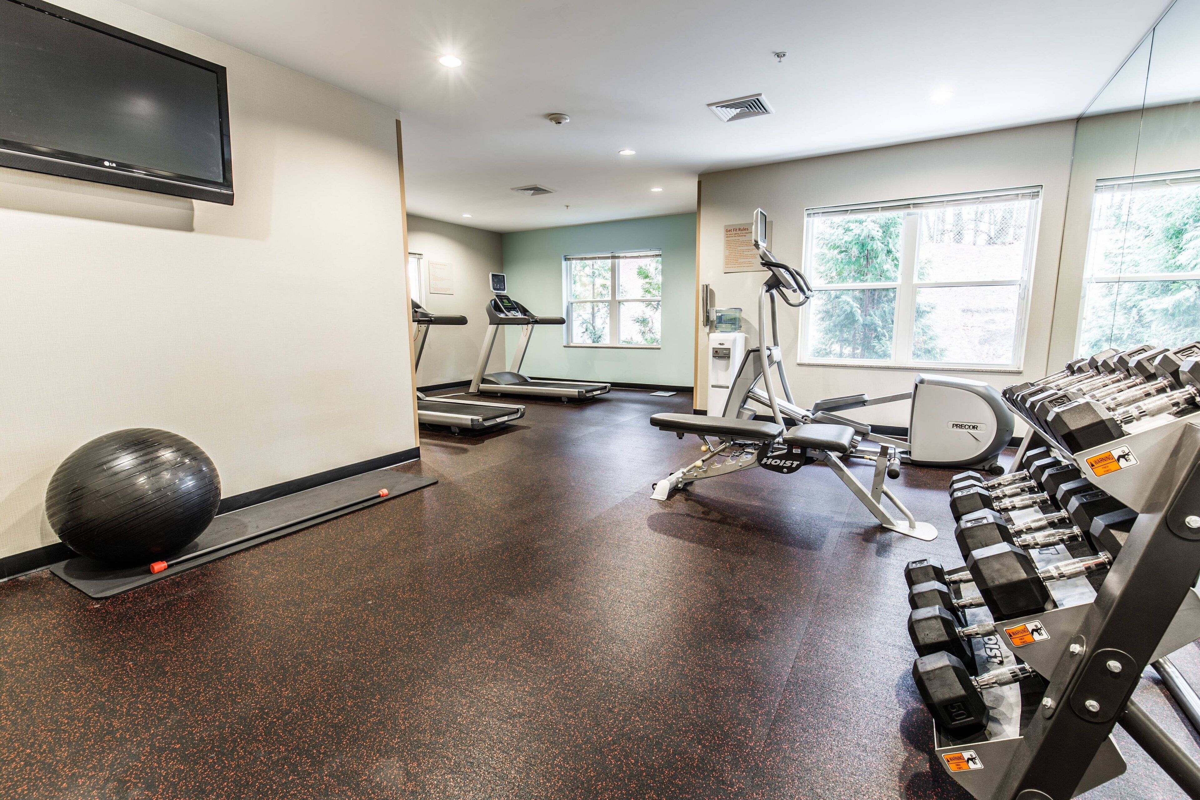 A gym with treadmills, a stationary bike, and a rack of dumbbells.