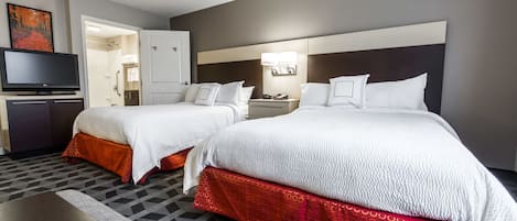 Una habitación de hotel con dos camas, televisión, escritorio y baño.