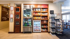 Un hall d’hôtel doté d’un espace de libre-service pour les boissons, de présentoirs à collations et d’un distributeur d’eau potable.