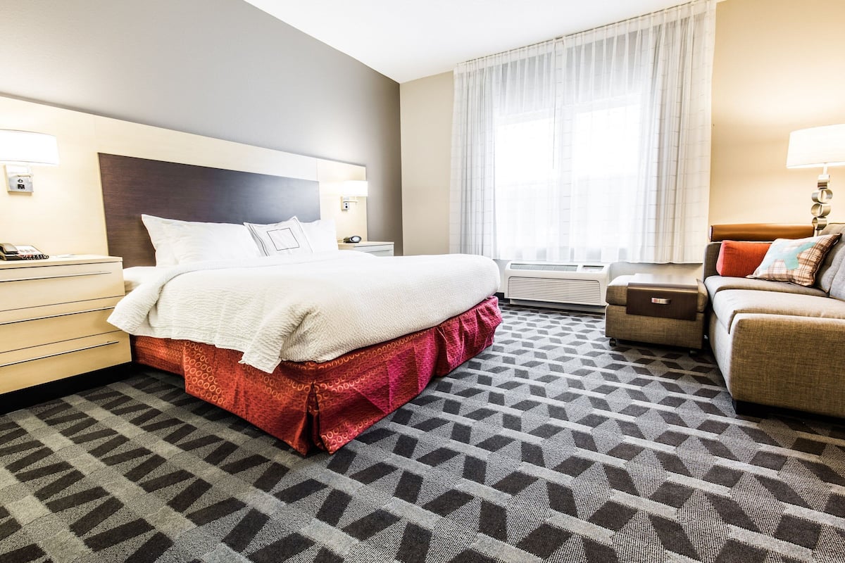 Een hotelkamer met een groot bed, een bank, een bureau en een raam met gordijnen.