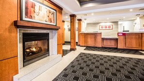 Un hall d’entrée avec une cheminée, un comptoir d’accueil en bois et un tapis à motifs.