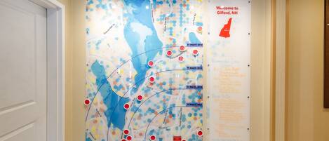Un pasillo con un mapa grande en la pared, un cartel de bienvenida y una lista de servicios.