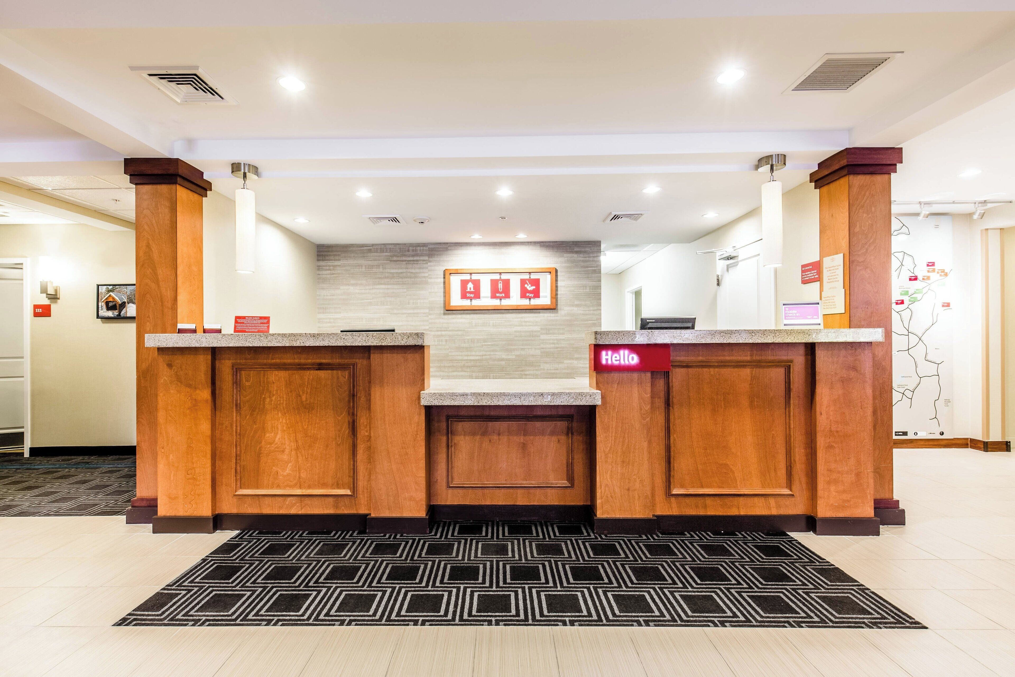 A reception area with a reception desk, a 'Hello' sign, a framed 'A' and 'B' sign, and a map on the wall.
