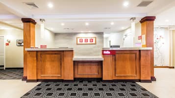A reception area with a reception desk, a 'Hello' sign, a framed 'A' and 'B' sign, and a map on the wall.