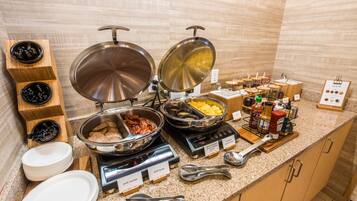 Una mesa de buffet con diversos alimentos y utensilios.