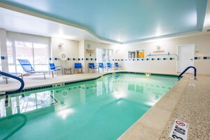 Una piscina interior con sillas azules, un letrero de salvavidas y un letrero que prohíbe el clavado.