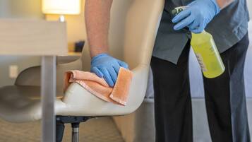 A person cleaning a chair with a cloth and a spray bottle.