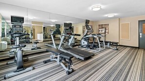 Une salle de sport équipée de tapis de course, de vélos d’appartement et d’appareils de musculation.