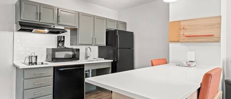 Una cocina moderna con gabinetes grises, un refrigerador negro, un microondas y una cafetera.