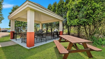 Un área de estar al aire libre techada, con una mesa de picnic y una parrilla.
