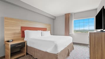 Una habitación de hotel con cama, mesita de noche, televisión y ventana con vistas.