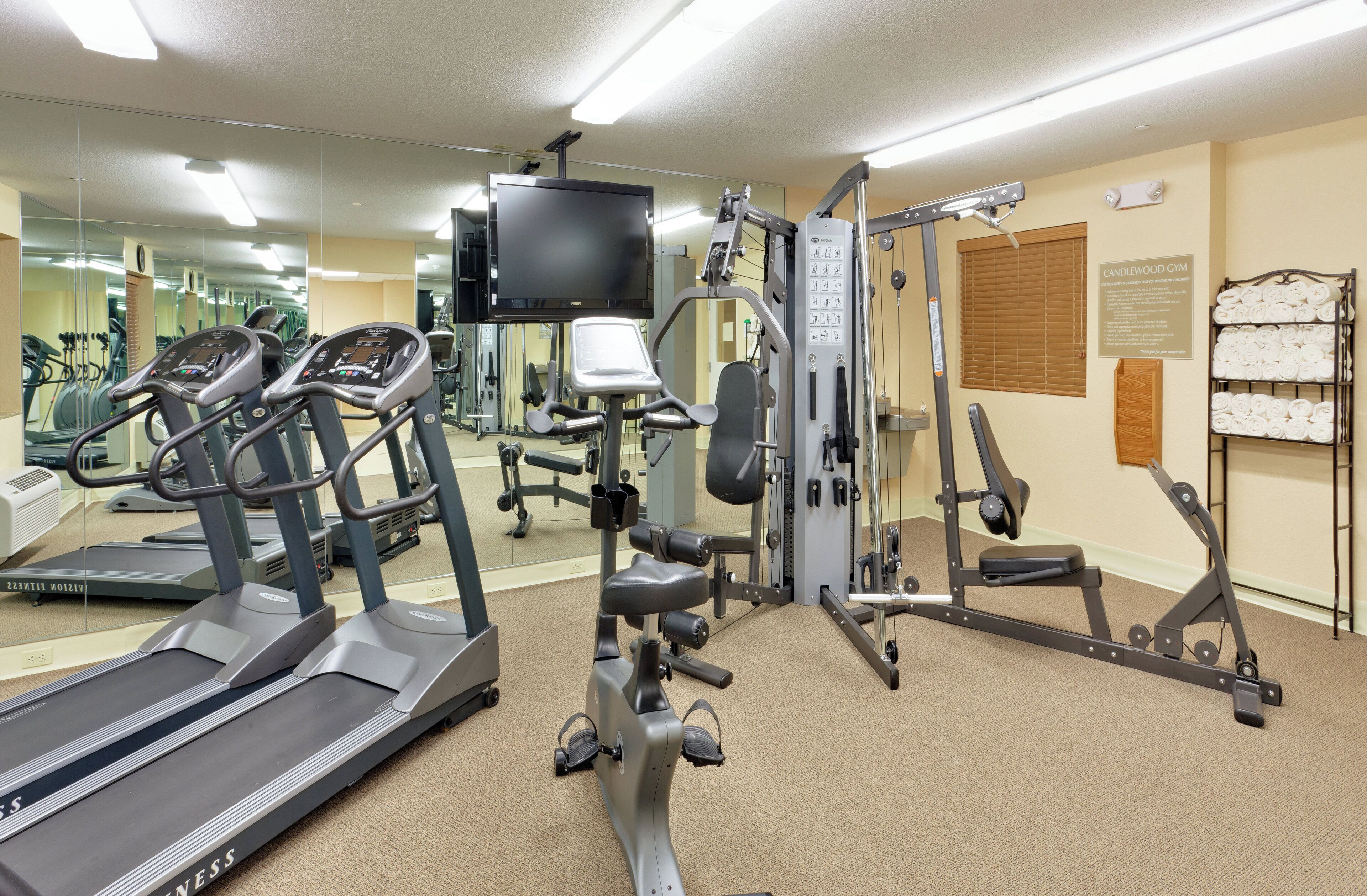 Un gimnasio con cintas de correr, máquinas de pesas y un muro de espejos.