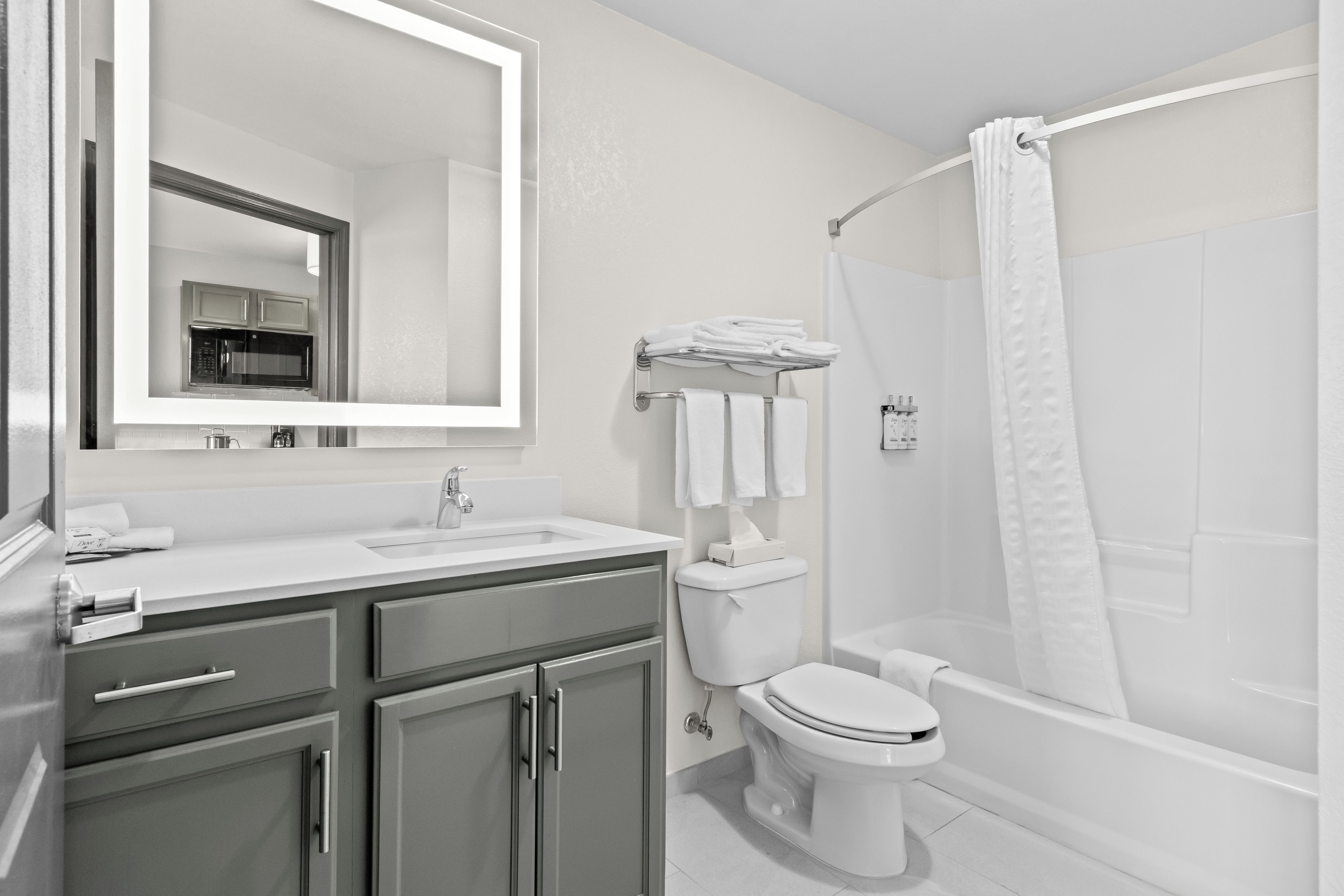 A modern bathroom with a sink, mirror, toilet, and shower area.