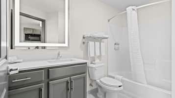 A modern bathroom with a sink, mirror, toilet, and shower area.