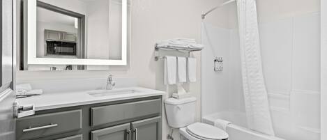 Un baño moderno con lavamanos, espejo, inodoro y zona de ducha.