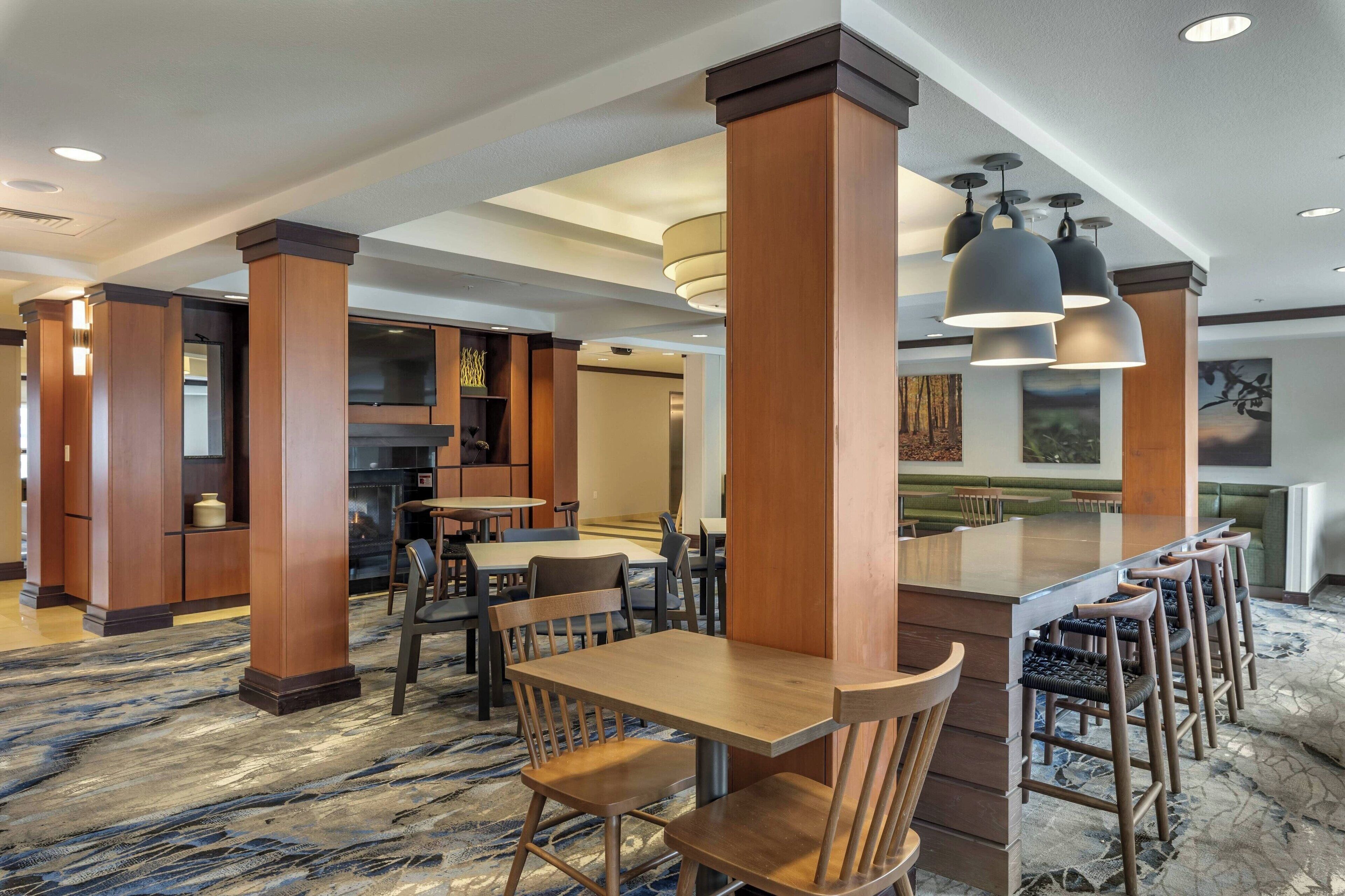 Un moderno vestíbulo de hotel con pilares de madera, una zona de bar y un área de estar.