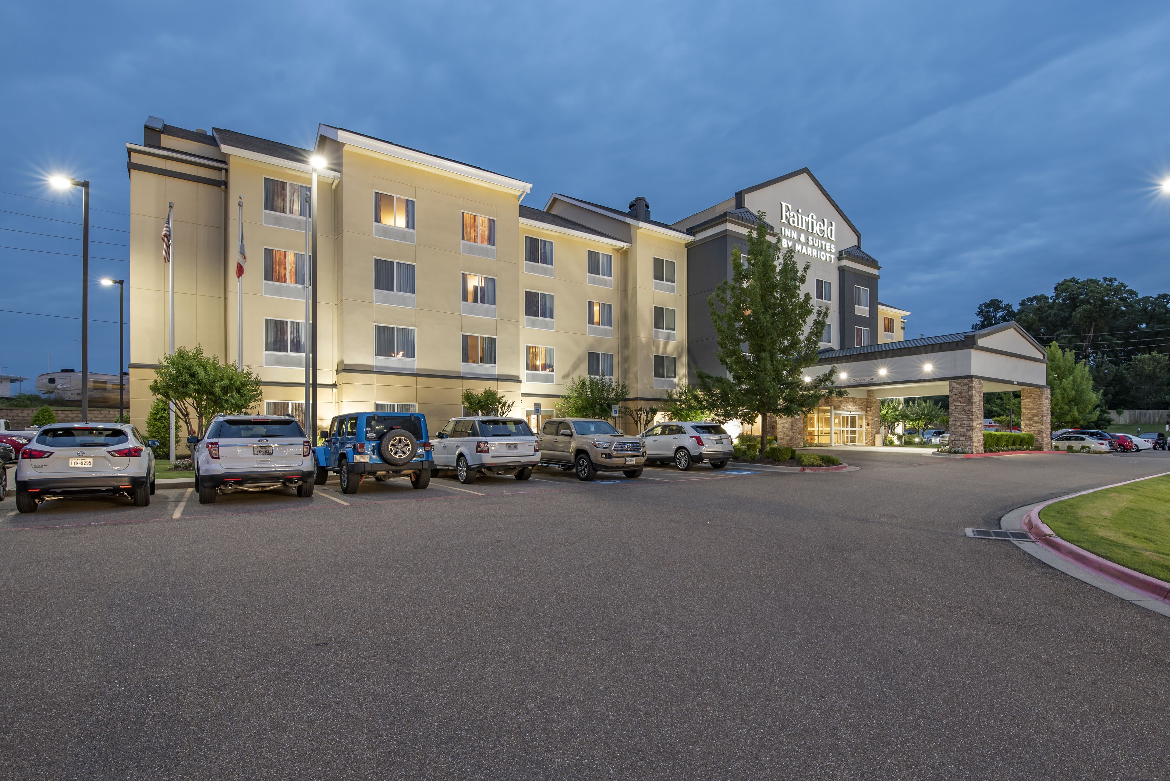 Et Fairfield Inn & Suites hotel med parkeringsplads og flere biler.