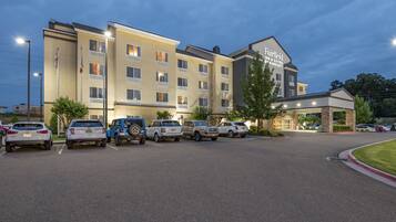 Et Fairfield Inn & Suites hotel med parkeringsplads og flere biler.