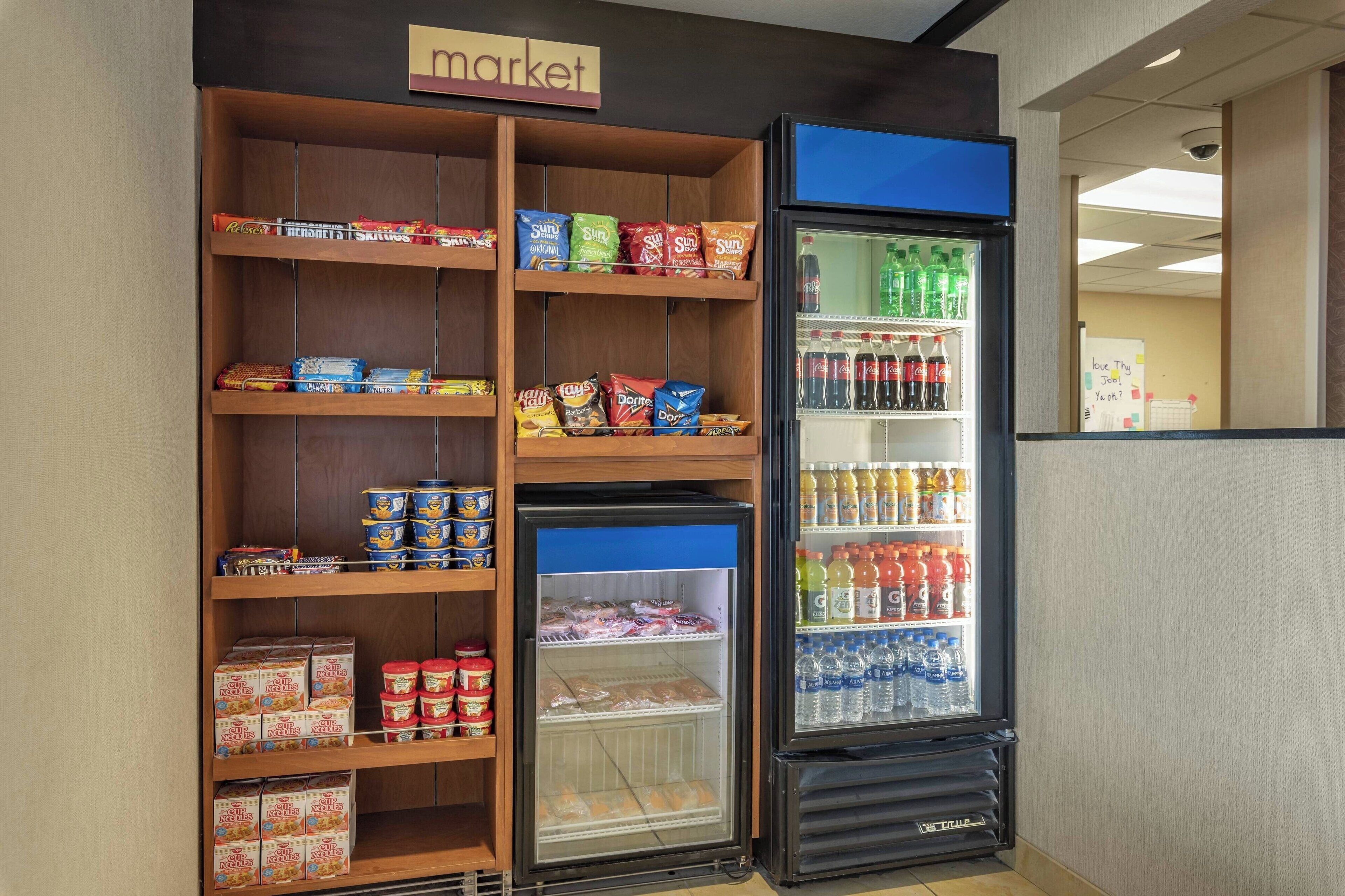 Esposizione di snack e bevande in un negozio, con una varietà di prodotti, bevande e un reparto refrigerato.