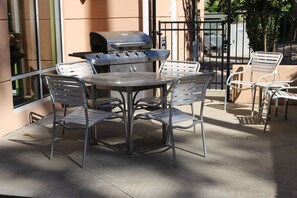 An outdoor patio with a round table and four chairs, a grill, and a metal fence. - Fairfield Inn & Suites by Marriott Texarkana (Texarkana)