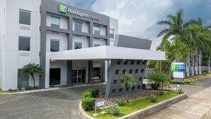 A Holiday Inn Express building with a modern design, featuring a large entrance canopy and a well-maintained landscaped area with palm trees and shrubs. - Holiday Inn Express San Jose Forum by IHG (Pozos)