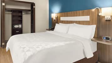 A hotel room with a large bed, a wardrobe, a bedside table with a lamp, and a nightstand with a phone.