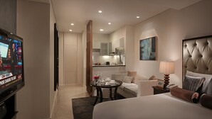 A hotel room with a large bed, a TV, a dining area, and a bathroom.