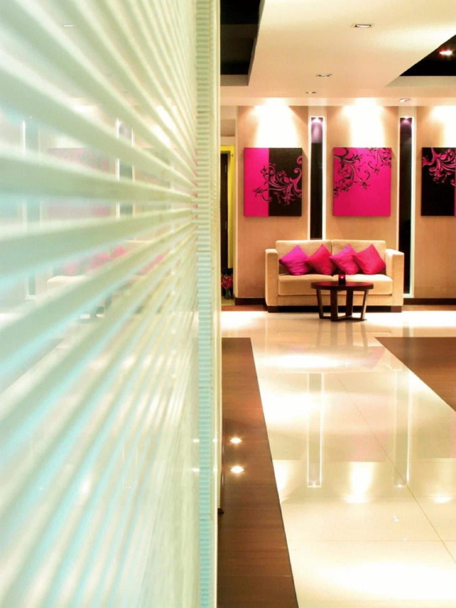 A modern lobby with a sofa and a table, a glass partition, and artwork on the walls.
