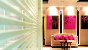 A modern lobby with a sofa and a table, a glass partition, and artwork on the walls. - Grand Inn Hotel (Bangkok)