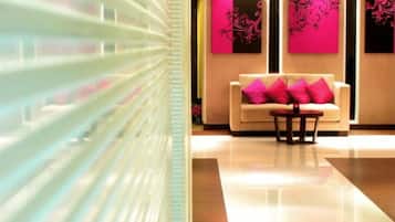 A modern lobby with a sofa and a table, a glass partition, and artwork on the walls.