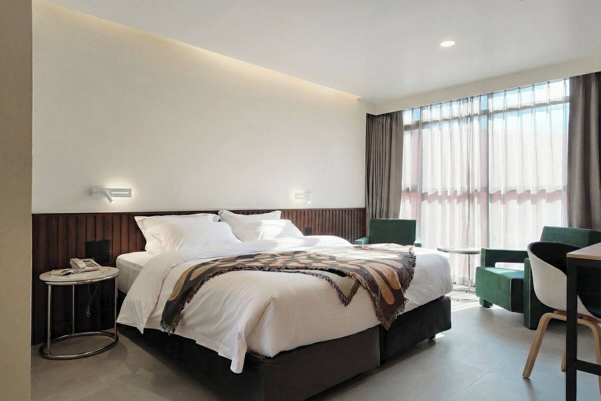 A modern hotel room with a large bed, bedside tables, a desk, and a chair.