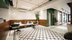 A modern lobby with a seating area, patterned floor, and a green-tiled wall. - Grand Inn Hotel (Bangkok)