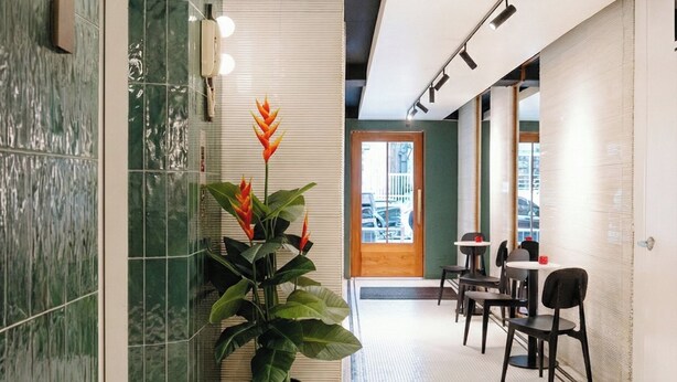 A modern interior with a green-tiled wall, a potted plant, and a seating area with tables and chairs. - Grand Inn Hotel (Bangkok)