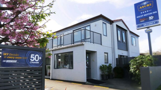 A modern two-story building with a balcony, a sign indicating 50+ channels, and a SKY Decoder in every room.