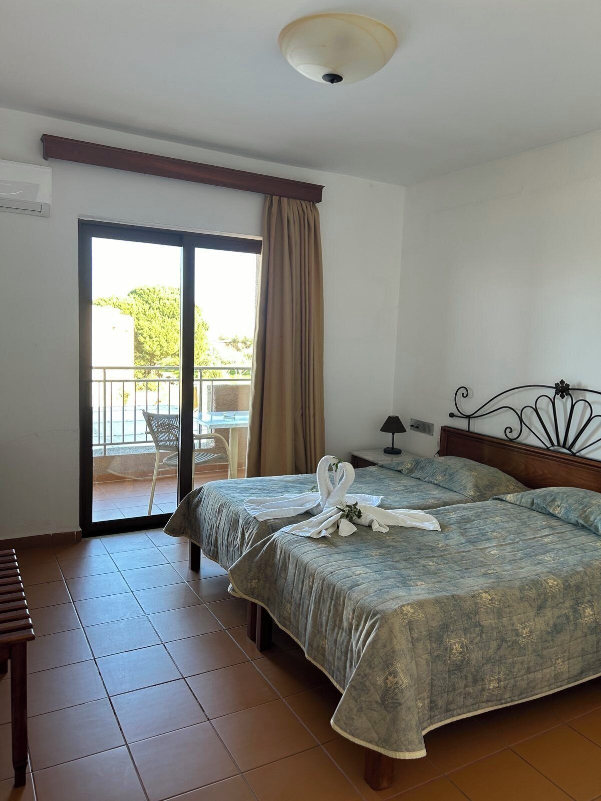 Une chambre d’hôtel avec deux lits, un balcon et une vue sur la verdure environnante.