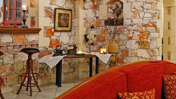 Uma sala de estar acolhedora com uma parede de pedra, um sofá vermelho e uma mesa de centro de madeira.