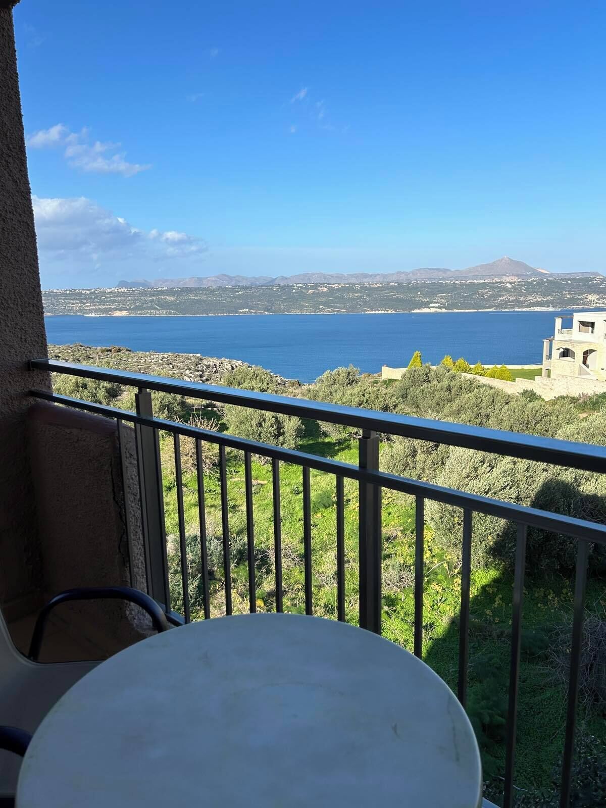 A balcony with a view of a body of water and distant mountains.