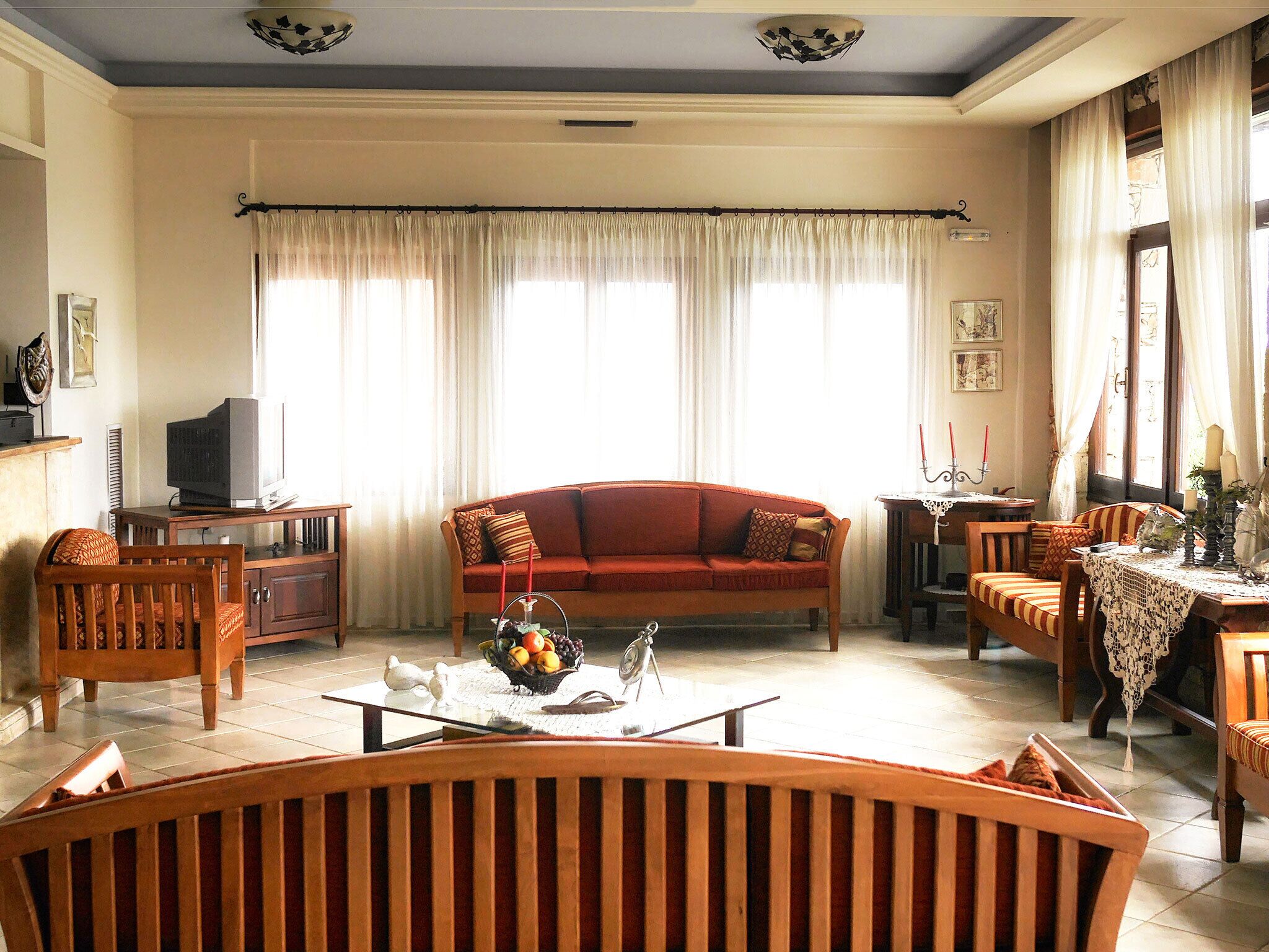 A living room with a sofa, chairs, a coffee table with fruit, and a television.