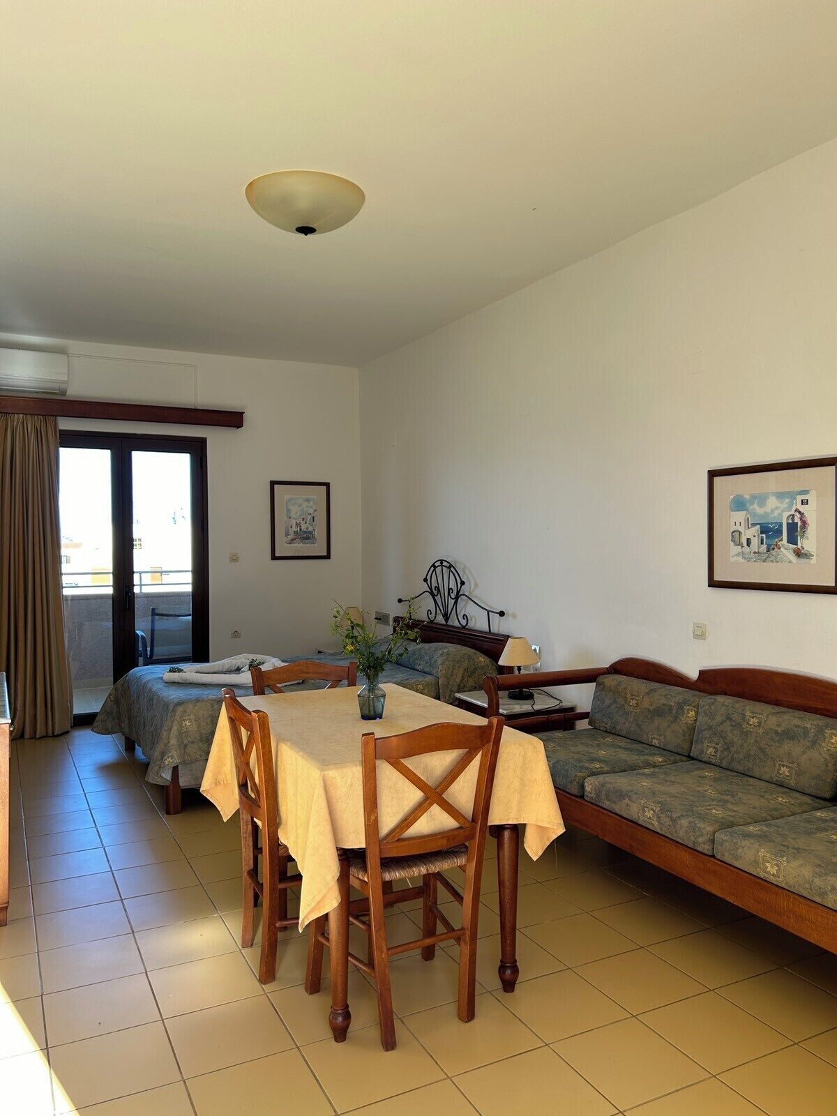 Une chambre d’hôtel équipée d’une table à manger, de deux lits, d’un canapé et d’un balcon avec des rideaux.